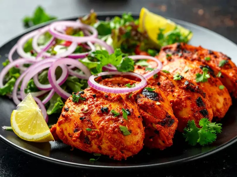 Marinaded tandoori BBQ chicken thighs in bowl with