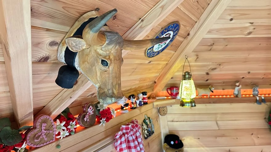 A wooden carving of a cow's head on the interior roof of a grill cabin. There are other trinkets decorating the edge of a cabin following a red, white and blue colour theme.