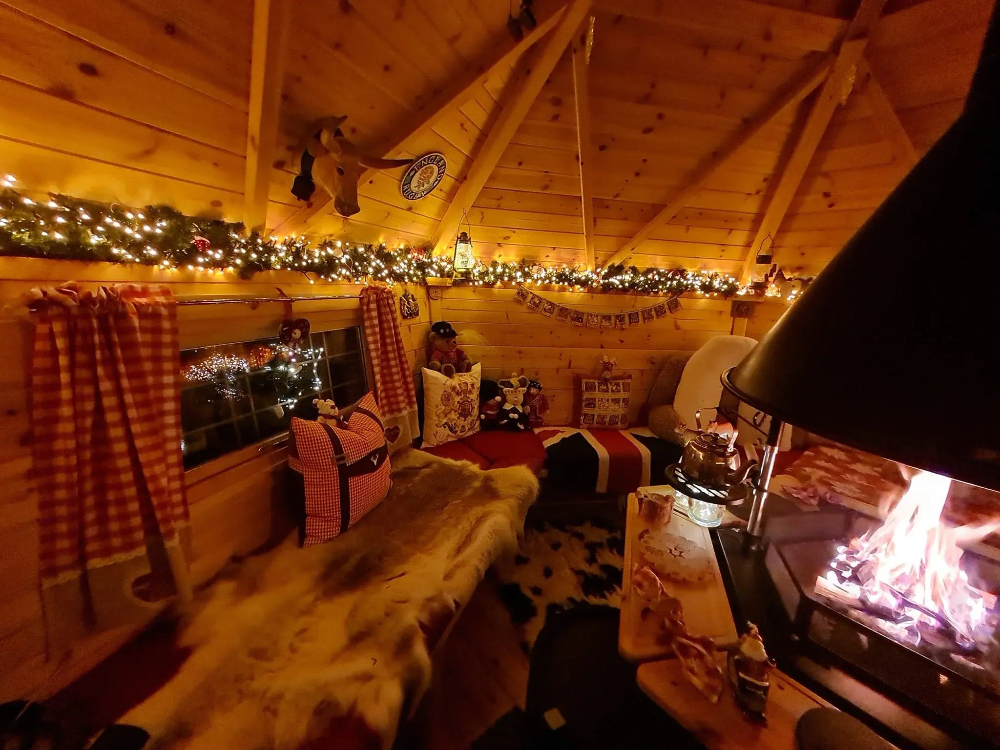 A cosy BBQ hut lit by fairy lights around the roof and the fire burning in the central grill.