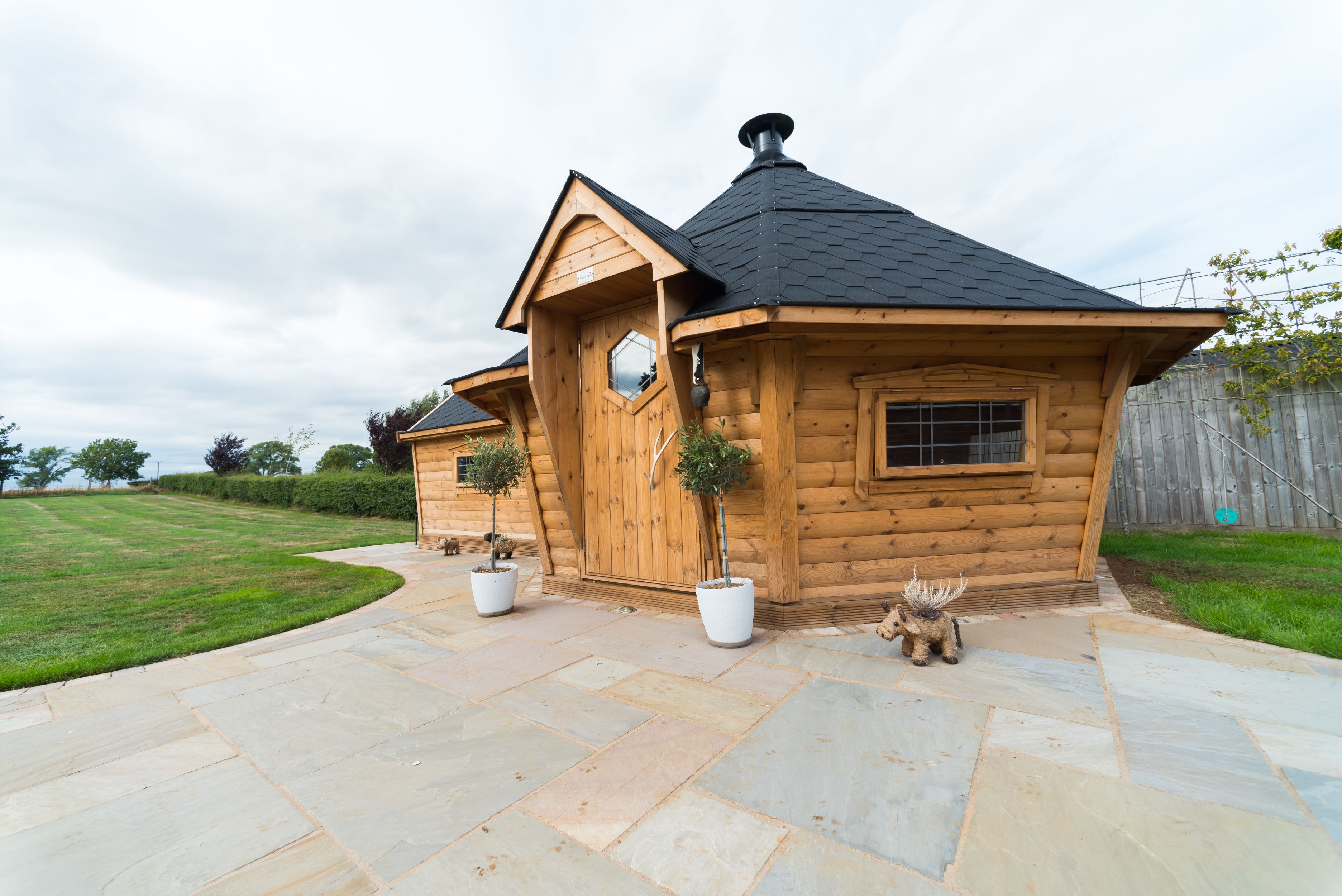 A 17m2 BBQ hut with a side extension on a patio.