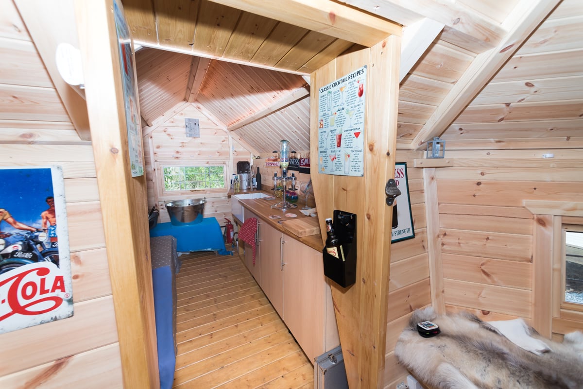 A BBQ hut extension with kitchen cupboards, a sink and cocktail making equipment.
