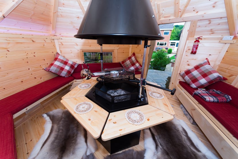 The interior of 10m2 BBQ cabin. The cabin benches have red pillows and chequered throw cushions.