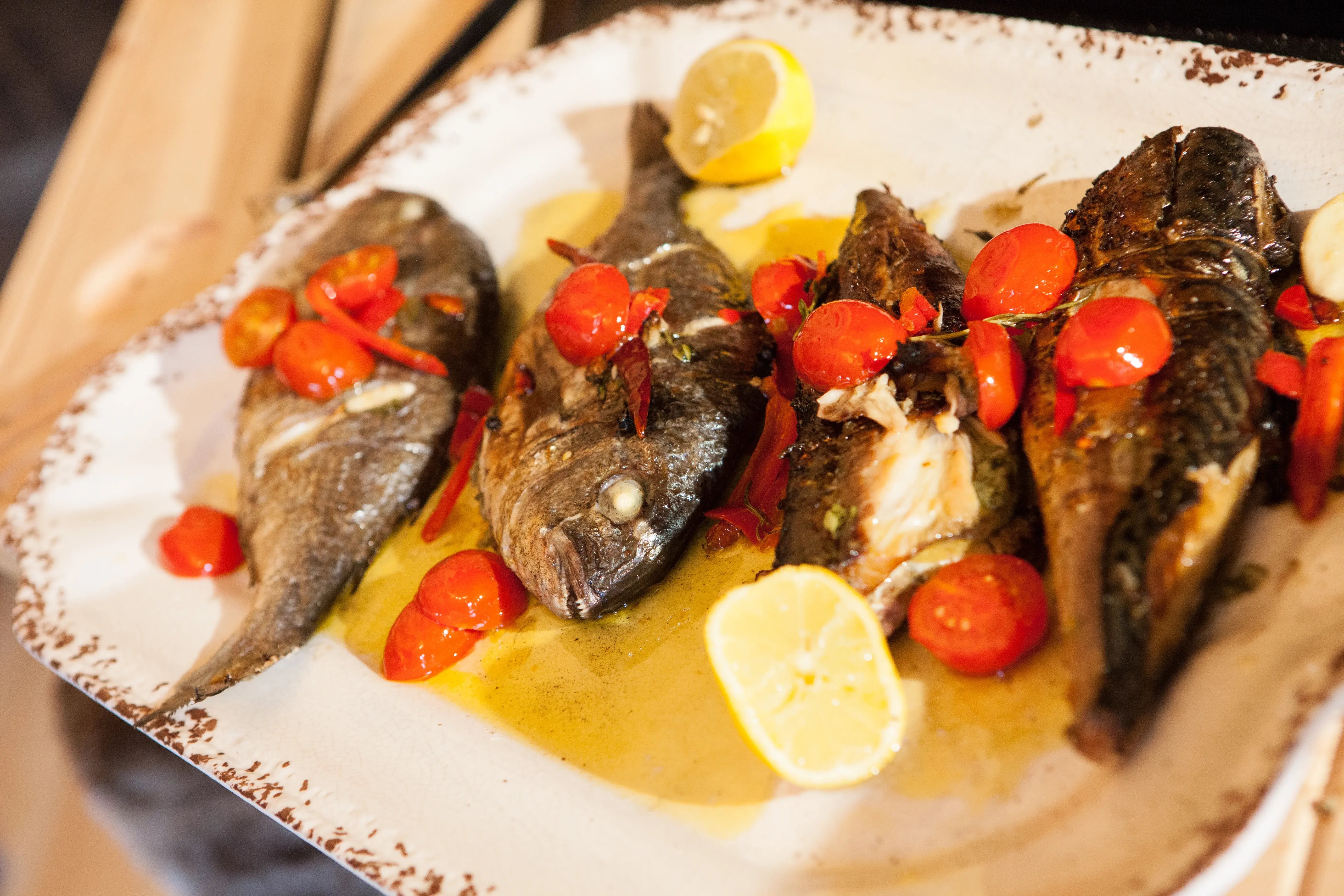 Grilled fish the tomatoes, olive oil, rosemary and lemon wedges