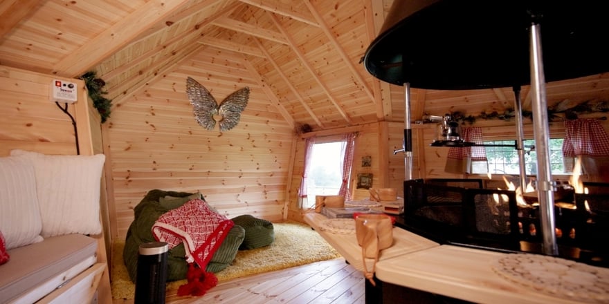 Cosy interior of 14m² BBQ cabin with central grill, wraparound seating and winter chalet decorations