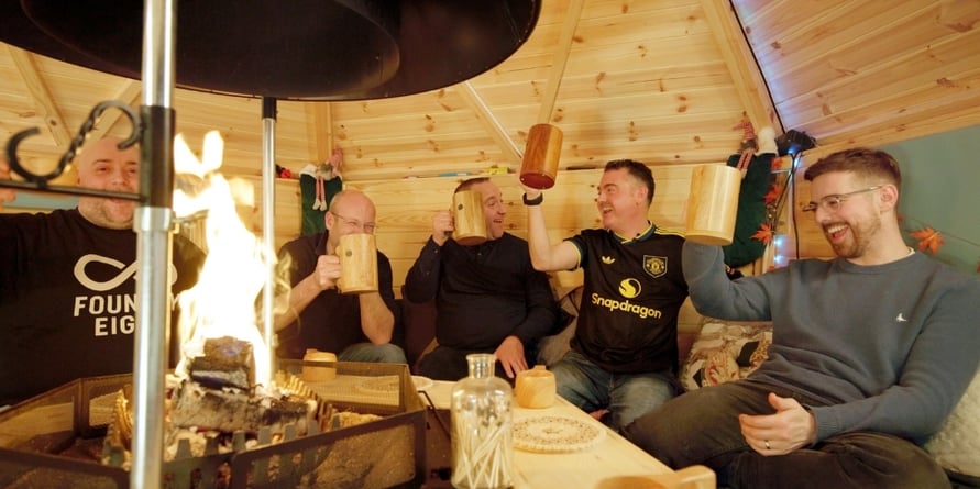 friends enjoying a drink together around the fire inside a barbecue hut