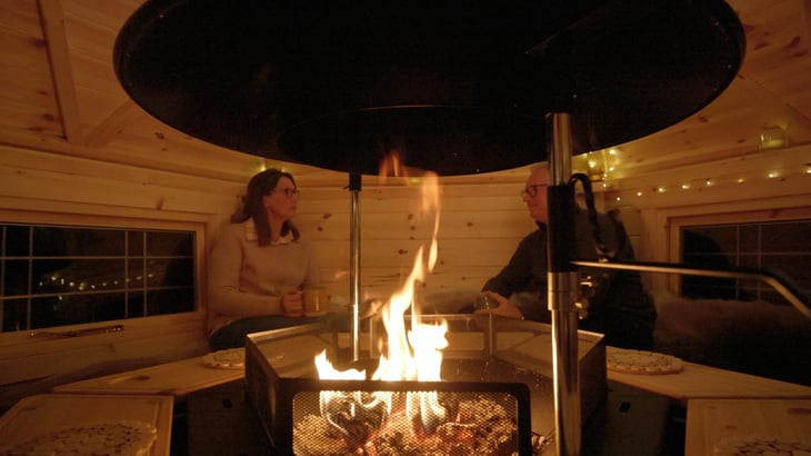 A couple sat opposite each other in a 7m2 BBQ hut