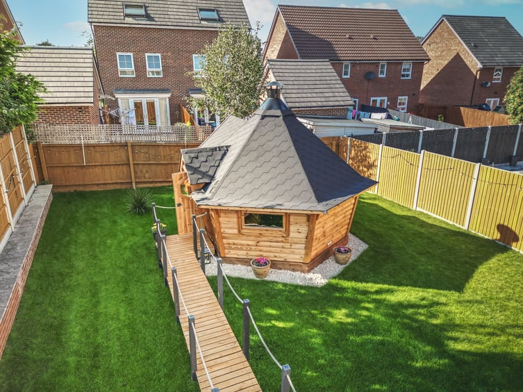 A 10m2 extended garden bar in the middle of a lawn with timber decking leading up to the door.