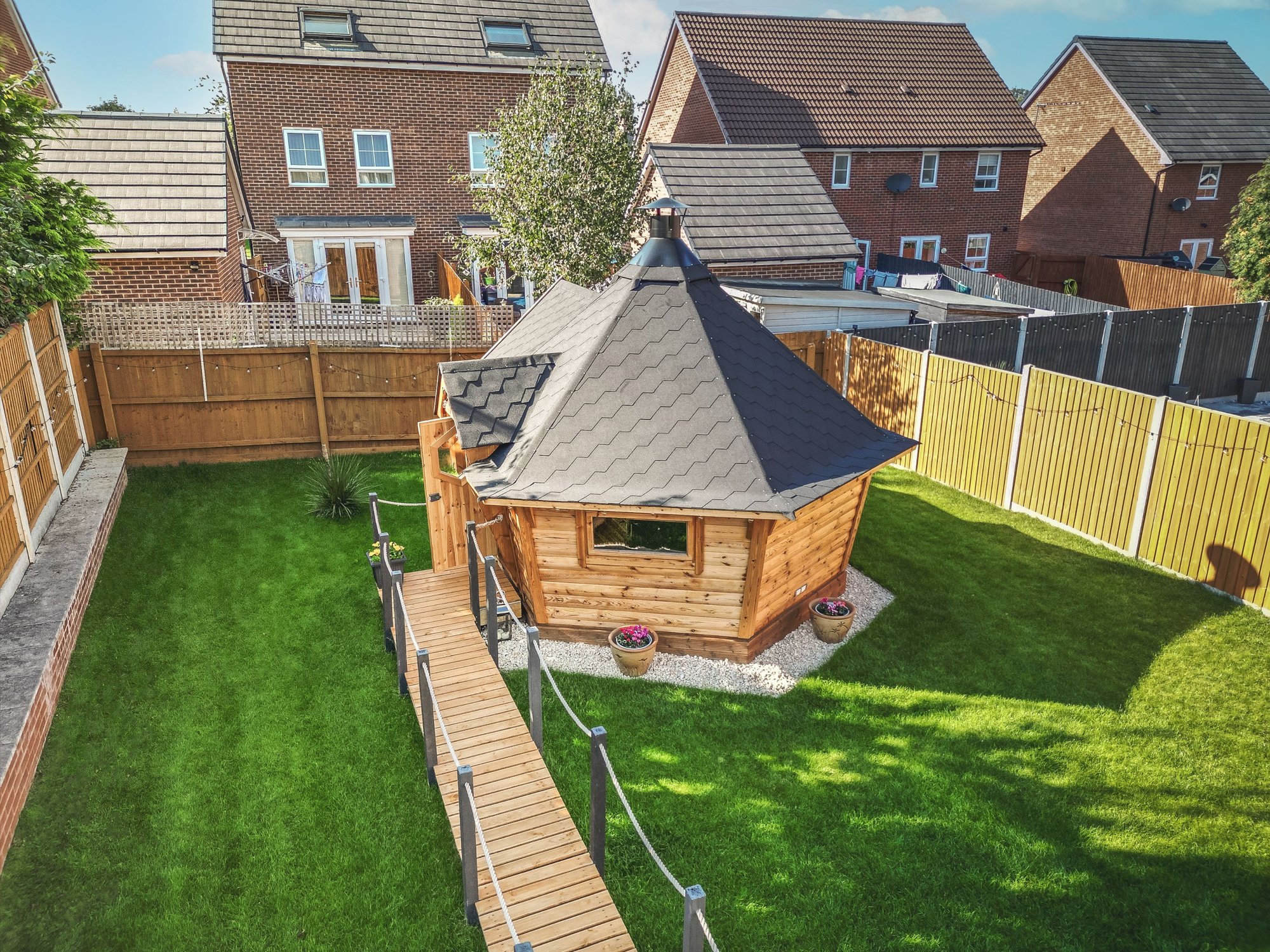 BBQ Hut with black roof and decking leading upto the doorway 
