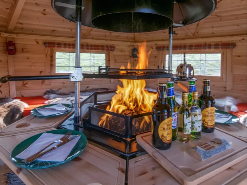 The central grill of a 10m² BBQ hut, with bottles of drink, plates and cutlery surrounding the grill.