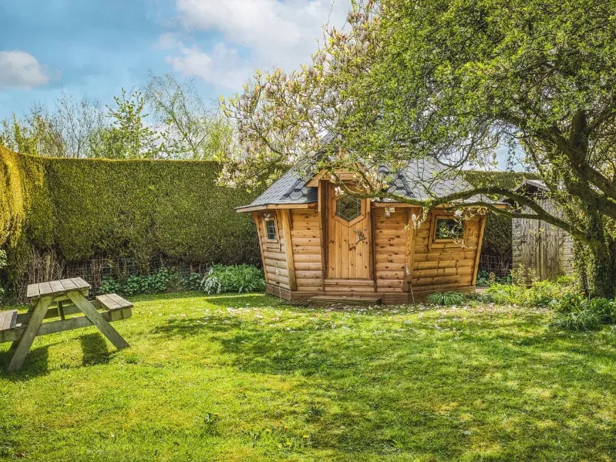 Traditional wooden barbecue hut in a spacious garden with surrounding lawn