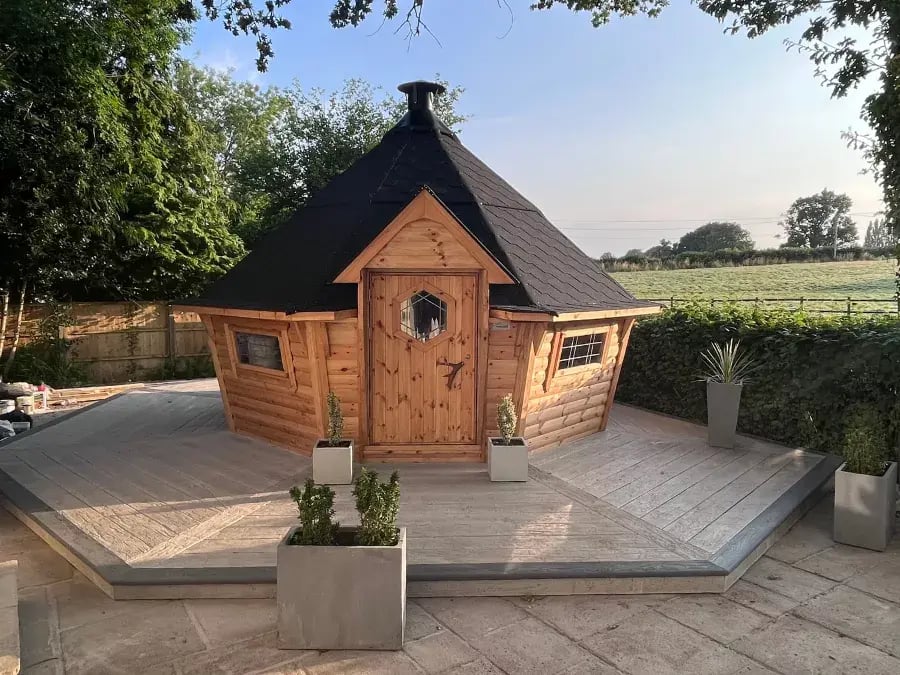 Barbecue house with black roof in modern garden on a wooden decking