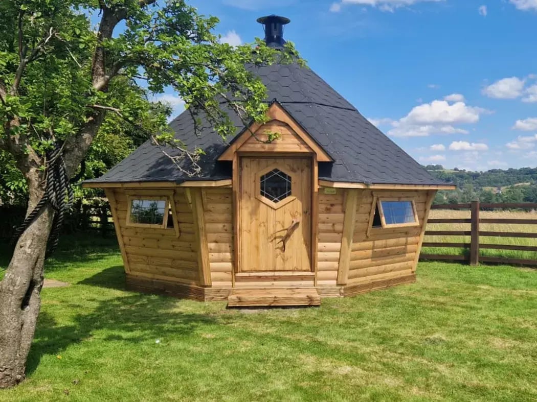 Large BBQ cabin installed in a landscaped garden with modern Scandinavian hut styling