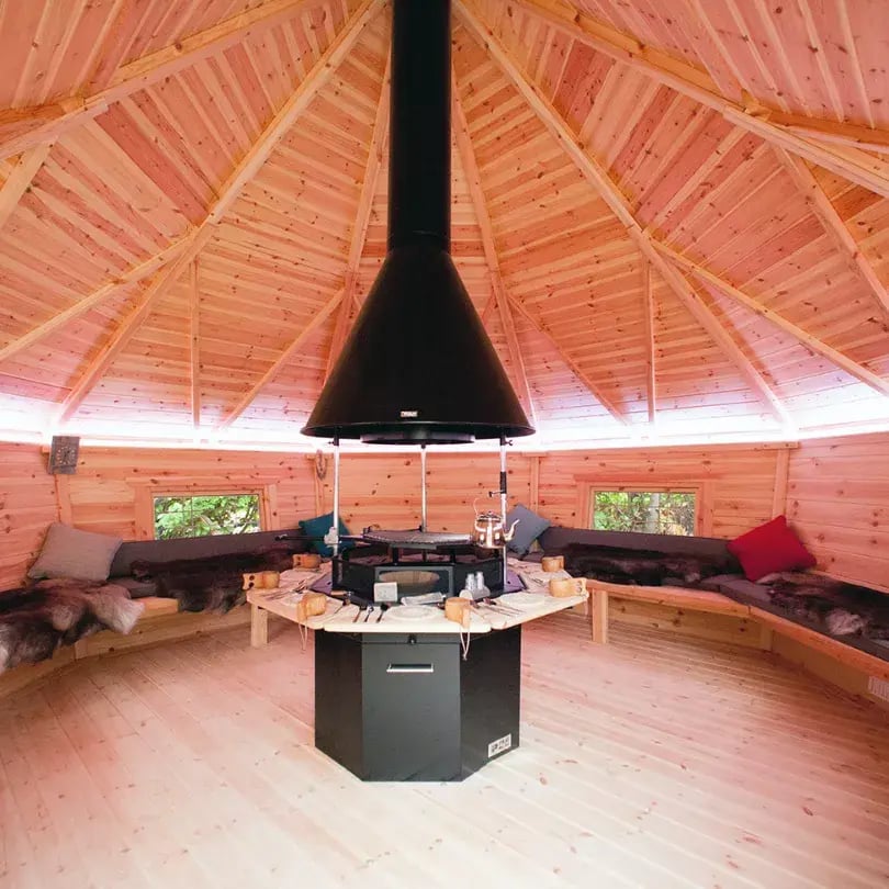 Interior of a 17m2 BBQ grill hut with reindeer skin throws and cushions.