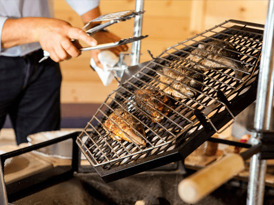 cooking fish on bbq grill inside a timber cabin
