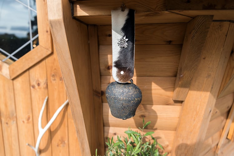 Close up the exterior of Arctic Cabin redwood, antler door handle and cowbell