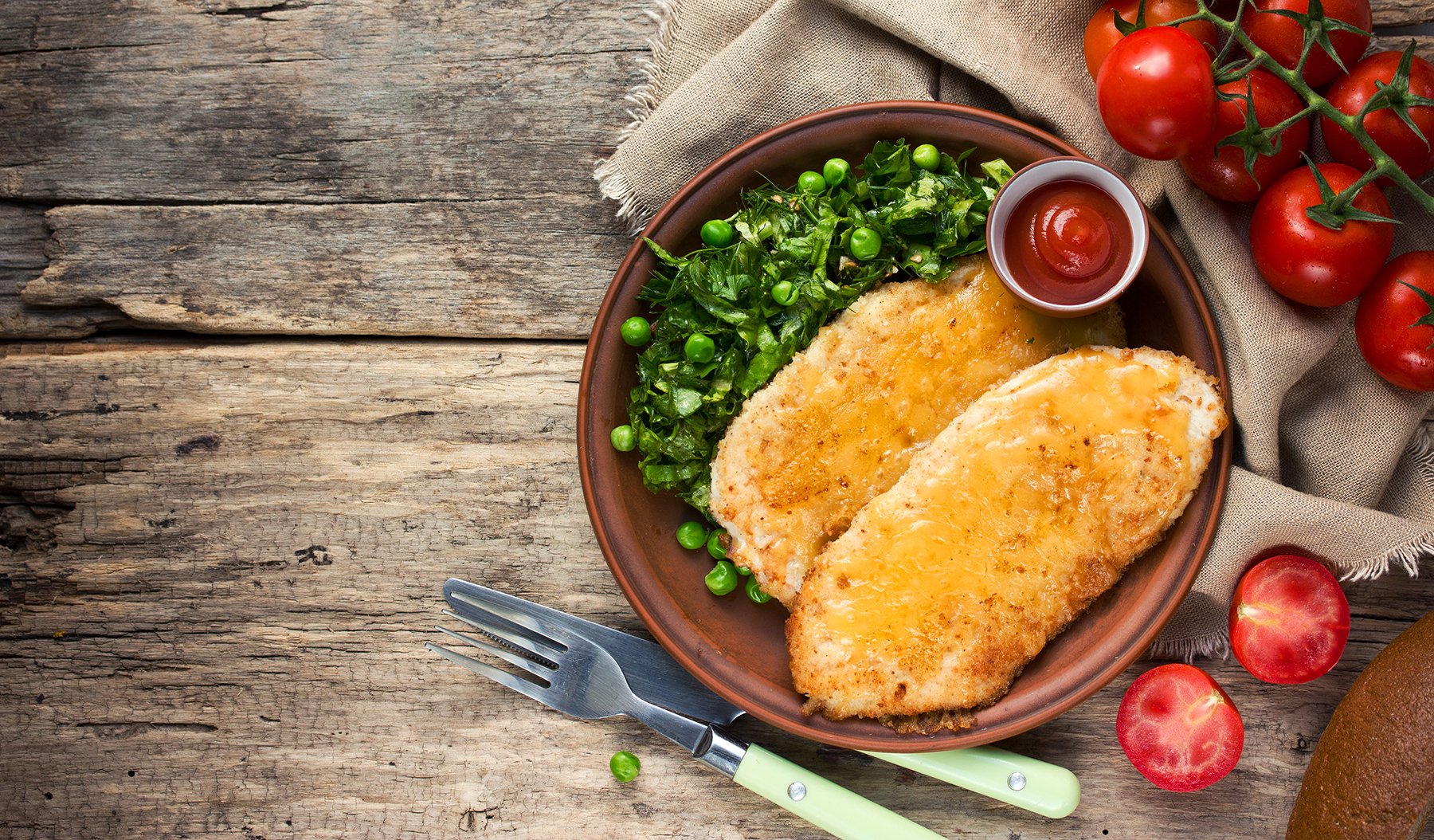 Breaded chicken escalopes in bowl, with garnish and tomatoes
