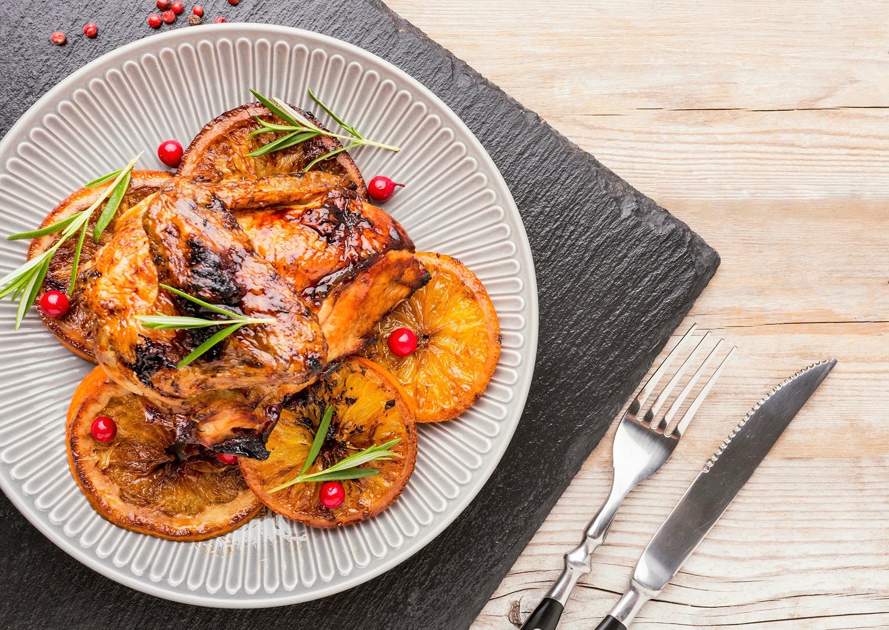 Barbecued Chicken wings with orange slices, rosemary and berries