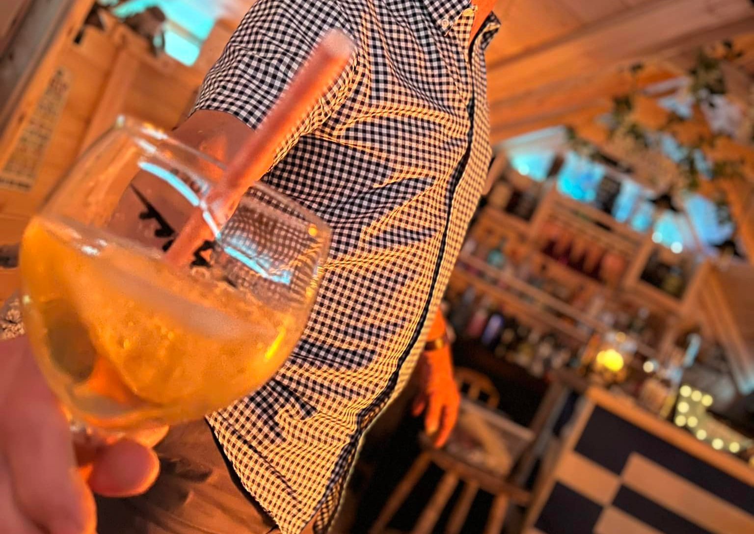 Man holding drink inside Arctic Cabin BBQ Hut garden bar
