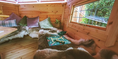 Interior of a BBQ cabin with Scrabble out on the reindeer skins laid over the benches