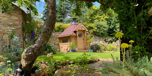 Small BBQ hut with red roof set within a beautiful leafy garden