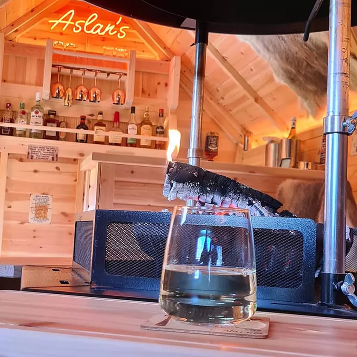 A short drinking glass sat in front of an indoor BBQ unit.