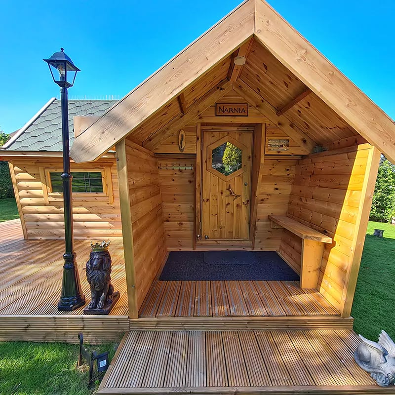 10m2 Arctic Garden Bar with a porch exterior with a lamp post and lion statue. The sign above the cabin door says "Narnia"