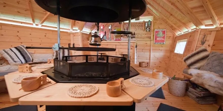 Spacious barbeque cabin with a central BBQ grill, wraparound seating and a traditional pub shed bar area.