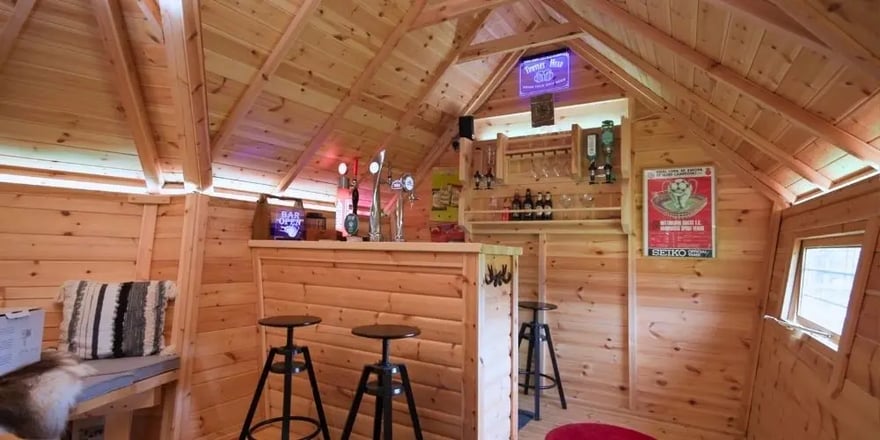 Close-up of a large garden bar inside a wooden barbeque cabin, complete with beer pumps and glass storage.