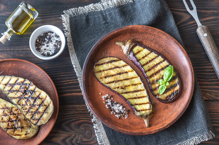 Chargrilled aubergine pieces on plate with sauces