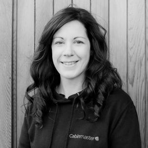 Black & White photo of Victoria Parkinson, Head Of Marketing at Arctic Cabins in front of a cedar garden room by sister company Cabin Master