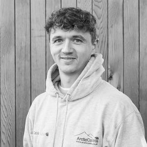 Black & White photo of Adam Males, Installations Team Leader at Arctic Cabins in front of a cedar garden room by sister company Cabin Master