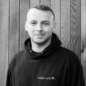 Black & White photo of George Jefferies, Sales Executive at Arctic Cabins in front of a cedar garden room by sister company Cabin Master