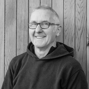 Black & White photo of Pete Dann at Arctic Cabins in front of a cedar garden room by sister company Cabin Master