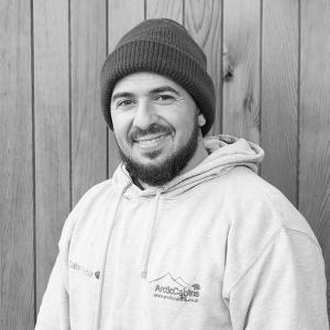 Black & White photo of Tod, Installations Team Leader at Arctic Cabins in front of a cedar garden room by sister company Cabin Master