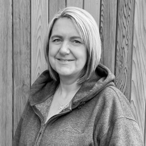 Black & White photo of Nikki Macpherson, Logistics Manager at Arctic Cabins in front of a cedar garden room by sister company Cabin Master