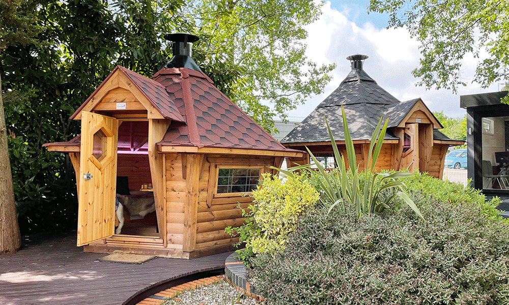 A red roofed sloping walled 7m BBQ Cabin by Arctic Cabins at the Nottingham Show Site