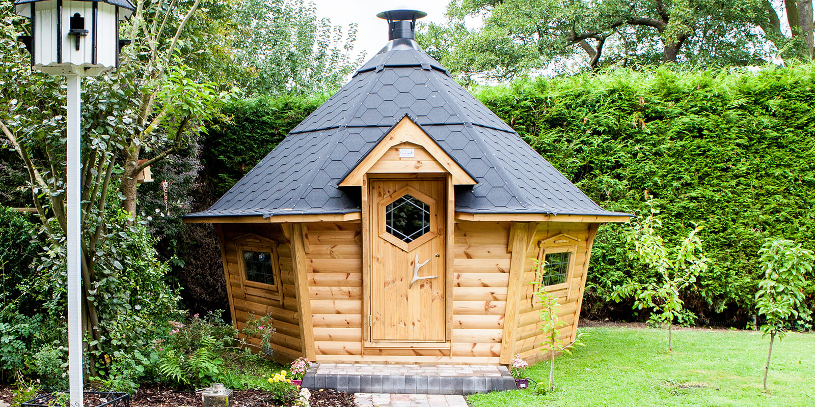 Medium sized BBQ cabin with black roof in nice, neat garden
